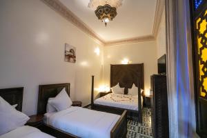 1 dormitorio con 2 camas y lámpara de araña en Riad Anis Fes, en Fez
