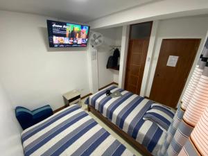 una camera con due letti e una TV a parete di Hostal Venus - Nueva Imagen a Huacho