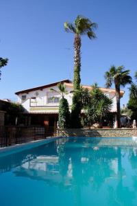 una piscina con una palmera y un edificio en Mediterraneo Residence, en Sciacca