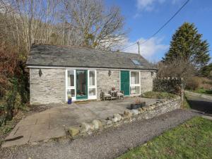 a stone cottage with a patio in front of it at Llo Bach Bach in Abergele