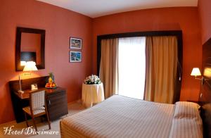 a bedroom with a bed and a desk and a window at Hotel Diecimare in Cava deʼ Tirreni