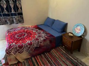 Bougainvillea studio في دهب: غرفة نوم مع سرير و كومودينو مع بطانية حمراء و زرقاء