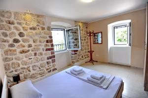 a bedroom with a white bed in a stone wall at Apartments Ave R in Kotor