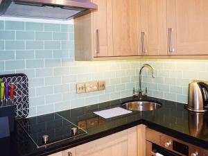 a kitchen with a sink and blue tiles on the wall at Salcombe 16 in Salcombe