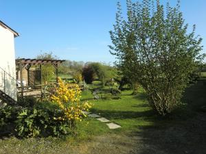 einen Garten mit einem Baum, einem Pavillon und Blumen in der Unterkunft Chambres La Guéjaillière in Beaumont-Pied-de-Boeuf