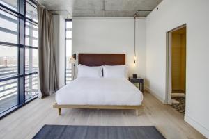 a bedroom with a white bed and large windows at Boro Hotel in Queens
