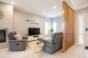 a living room with two chairs and a television at Family Tides Beach House in Rosebud