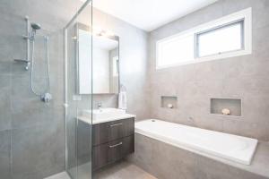a bathroom with a tub and a sink and a shower at Family Tides Beach House in Rosebud +21 photos