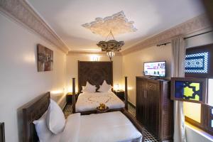 1 dormitorio con 2 camas y TV de pantalla plana en Riad Anis Fes en Fez