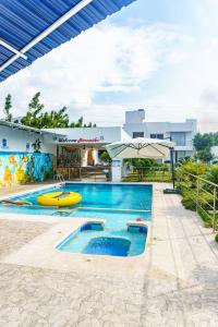 a pool at a resort with an umbrella at Casa finca con piscina in Santa Marta