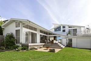 a large white house with a yard at The Loft @ Mollymook 70s Beach House in Mollymook