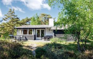 Gorgeous Home In Nex With Kitchen في Vester Sømarken: كابينة صغيرة أمامها طاولة وكراسي
