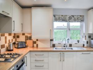 a kitchen with white cabinets and a sink at Crab Cottage in Sutton on Sea