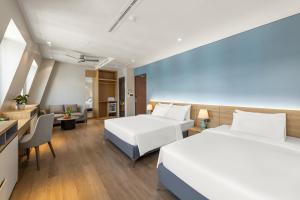Una habitación de hotel con dos camas y una sala de estar. en Laputa Hotel Phú Quốc, en Phu Quoc