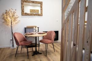 a table with two pink chairs and a mirror at Les alouettes in Caudry
