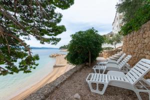 eine Reihe weißer Stühle neben einem Strand in der Unterkunft Apartments Beach Dream in Mimice