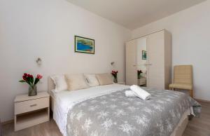 ein weißes Schlafzimmer mit einem Bett und einem Stuhl in der Unterkunft Apartments Beach Dream in Mimice