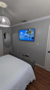 a bedroom with a white bed and a tv on the wall at Luxurious Home, Accommodating Two Master Bedrooms with great amenities. in Tamiami