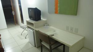 a room with a desk with a tv on top of it at Apartamento Le Jardin - Suítes para Temporada in Caldas Novas
