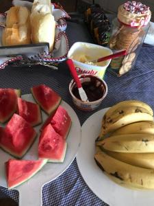 a table with plates of watermelon and bananas and bread at CAPIVARI POUSADA B&B in Capivari