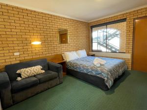 a bedroom with a couch and a bed and a chair at Lake Mulwala Hotel in Mulwala