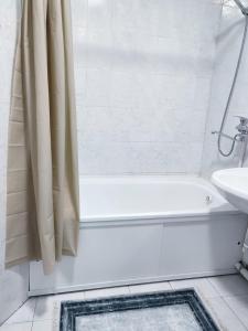 biała łazienka z wanną i umywalką w obiekcie Апартаменты Жаяу Мусы 7А w mieście Pawłodar
