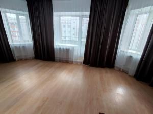 an empty room with two windows and a wooden floor at Апартаменты Жаяу Мусы 7А in Pavlodar