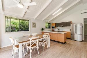Una cocina con mesa y sillas y un refrigerador. en Seashells - Popular Beach House, en Yamba