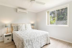 Una habitación blanca con una cama y una ventana en Seashells - Popular Beach House, en Yamba