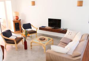 sala de estar con sofá, sillas y TV en Les Patios de Grands Bois, en Saint-Pierre