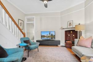 a living room with a couch and a tv at Discover The Rocks - Historical Terrace House in Sydney