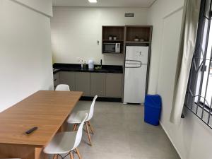 Il comprend une cuisine équipée d'une table en bois et d'un réfrigérateur blanc. dans l'établissement Casa a 40 metros da praia, rua tranquila, à Penha