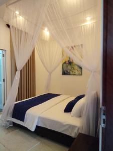 1 dormitorio con cama con dosel y cortinas blancas en The Moose Weligama en Weligama