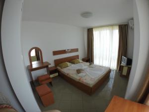 a small bedroom with a bed and a mirror at Hotel Filland in Sozopol