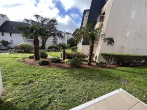 een tuin met palmbomen en struiken naast een gebouw bij Appartement Bénodet, 2 pièces, 2 personnes - FR-1-481-136 in Bénodet