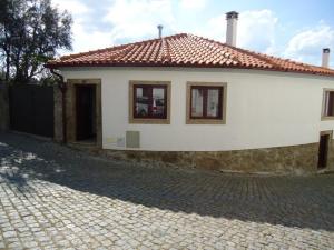 ein kleines weißes Haus mit einer steinernen Einfahrt in der Unterkunft Casas do Flor in Gouveia