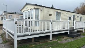 a white house with a porch and a white fence at Park Home at Lyons Winkups Holiday Park N.Wales in Kinmel Bay