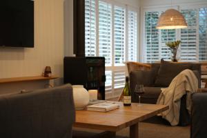 uma sala de estar com um sofá e uma mesa com um copo de vinho em The One at Pearl em Pearl Beach