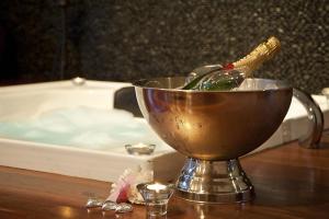 a bath tub with a bucket of water and a bottle of wine at Kudos Villas - Hepburn Springs in Hepburn Springs