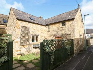 a stone house with a gate in front of it at Carter's Cottage in Stow on the Wold