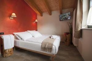 una camera con un letto bianco con una parete rossa di Maison d'hôtes Victoret a Challand Saint Victor