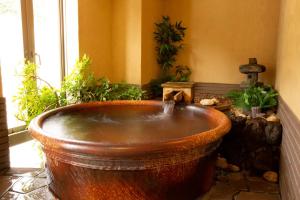 a large wooden tub in a room with plants at Oyado Seri in Toyooka