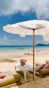 a white umbrella on a beach with chairs and a table at Kerala Coco Resort in Ko Samed