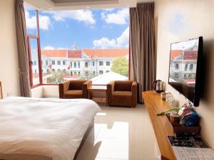 Nam ÐịnhにあるRuby Hotelのベッドと大きな窓が備わるホテルルームです。