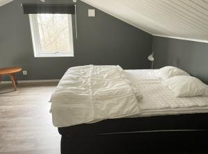 a large bed with white sheets and a window at Fantastic holiday home with own lake plot by Bolmen, Ljungby in Ljungby