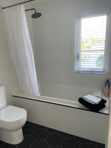 a white bathroom with a toilet and a window at Jetty Road Beach House in Rosebud