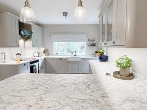 a kitchen with white cabinets and a marble counter top at Upalong in West Lulworth