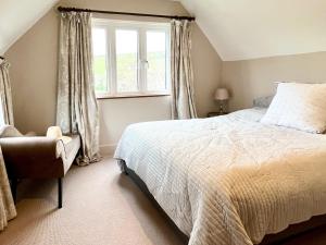a bedroom with a bed and a window and a chair at Upalong in West Lulworth