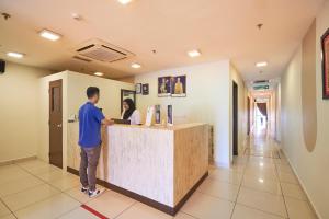 a man standing at a counter in a hospital lobby at Swing & Pillows - Adya Hotel Kuala Lumpur in Kuala Lumpur