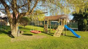 a playground with a tree and a swing at Apartman Barbara in Daruvar